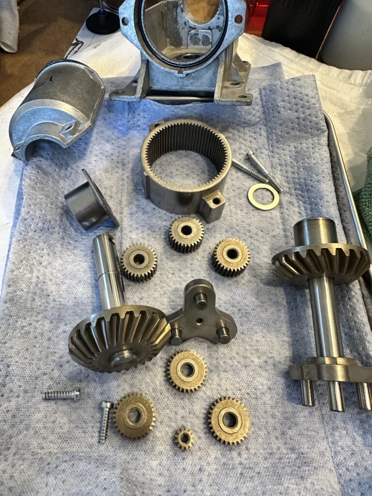 This is a photograph of the disassembled gear train from a KitchenAid "Pro Line" mixer, which design is shared with similar models. Visible are the drive gears, housing parts, and various hardware.