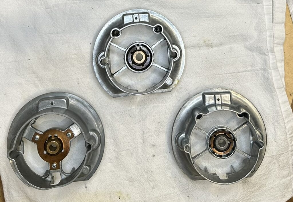 A photo showing three different generations of rear bearing bracket assemblies for KitchenAid mixers.