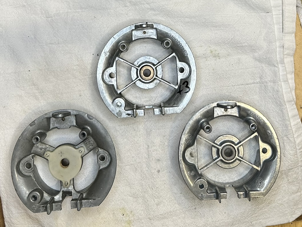 A photo showing three different generations of rear bearing bracket assemblies for KitchenAid mixers, as viewed from outside the mixer.